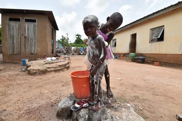 A girl from the Baoule community washes a child on March 31, 2018 in Assounvoue village, central Ivory Coast, on the eve of “Paquinou”, easter celebration traditionally marked by “palaver”, reconciliation, feast, music and dance. (Photo by Sia Kambou/AFP Photo)