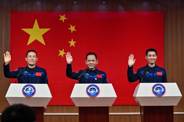 Astronauts for China's Shenzhou-21 space mission Zhang Hongzhang (L), Commander Zhang Lu (C) and Wu Fei (R) wave during a press conference a day before the launch of the mission at the Jiuquan Satellite Launch Centre in the Gobi desert, in northwest China on October 30, 2025. (Photo by Hector Retamal/AFP Photo)