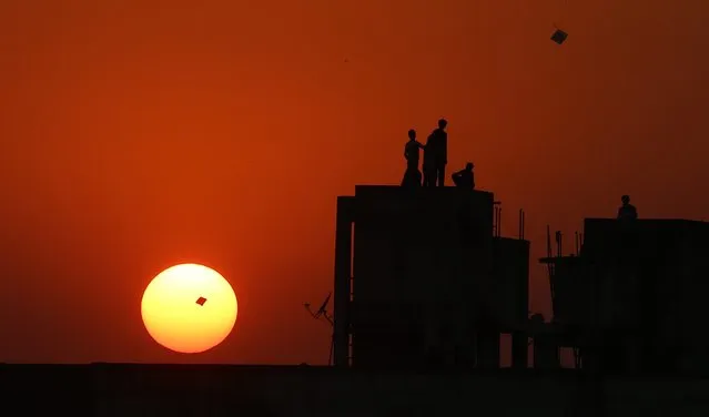 Indian people stands on the terrace of a building as they fly kites during a sunset in Ahmedabd, India, 06 January 2015. Kite-makers are preparing for the annual Hindu festival Makar-Sankranti (Uttarayan), during which people fly kites and compete in kite flying competitions. Makar-Sankranti is celebrated on 14 January of every year. (Photo by Divyakant Solanki/EPA)