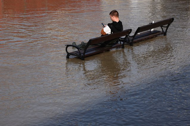 A person sits on a bench at the flooded Danube river boulevard as many parts of Central Europe were flooded due to heavy rains in Budapest, Hungary on September 18, 2024. (Photo by Jakub Porzycki/Anadolu via Getty Images)