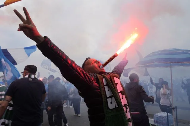 A Napoli fan celebrates, holding a flare in his mouth, after his team scored the first goal during the Series A soccer match against Salernitana, outside the Diego Armando Maradona stadium, in Naples, Italy, Sunday, April 30, 2023. (Photo by Gregorio Borgia/AP Photo)
