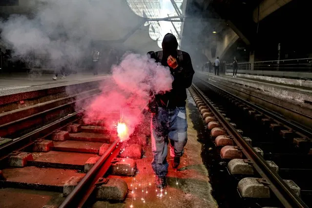 A protester lights a flare during a protest against French President's policy held by students and public railways trade unionist at Montparnasse train station on June 7, 2018 in Paris. Workers of the SNCF, France's heavily indebted state rail operator, will go on strike on June 7 and 8, 2018, as part of rolling train strikes set to last until June 28. (Photo by Zakaria Abdelkafi/AFP Photo)