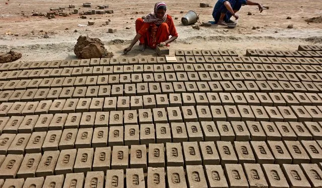 A woman organizes bricks at a kiln on the outskirts of Lahore, Pakistan, Sunday, March 7, 2021. (Photo by K.M. Chaudary/AP Photo)