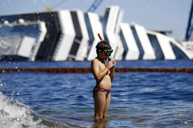 A boy prepares to snorkel in front of the wreckage of capsized cruise liner Costa Concordia, near the harbour of Giglio Porto in this August 28, 2012 file photo. (Photo by Alessandro Bianchi/Reuters)