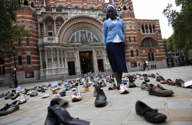 Catholic Agency For Overseas Development's (CAFOD) Sister Clara from Zambia, walks through shoes displayed outside Westminster Cathedral in central London on August 15, 2018. The shoes, which have been displayed outside Westminster Cathedral to promote Pope Francis' refugee campaign, which is calling for world leaders to back global agreements aimed at assisting refugees and migrants. (Photo by Andy Rain/EPA/EFE)
