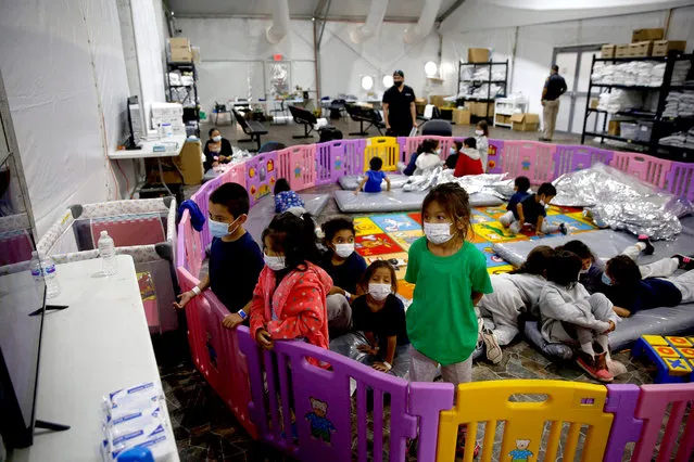 Young unaccompanied migrants, ages 3-9 watch TV inside a playpen at the Donna Department of Homeland Security holding facility, the main detention center for unaccompanied children in the Rio Grande Valley in Donna, Texas, March 30, 2021. The youngest of the unaccompanied minors are kept separate from the rest of the detainees. (Photo by Dario Lopez-Mills/Pool via AFP Photo)