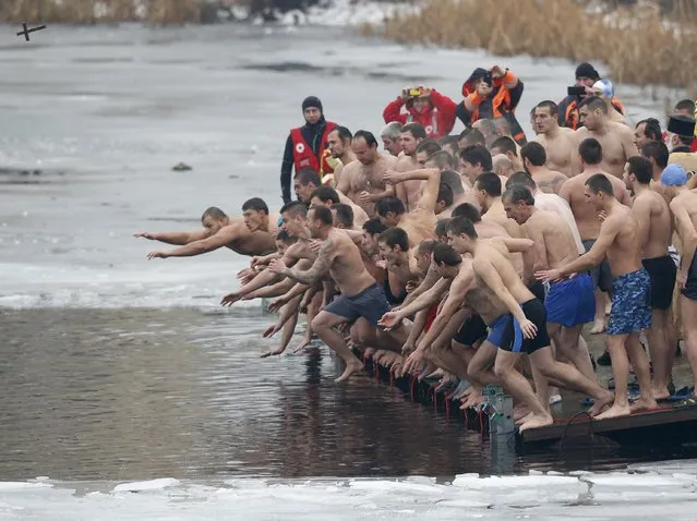 Men jump into the waters of a lake in an attempt to grab a wooden cross on Epiphany Day in Sofia, Bulgaria January 6, 2016. Orthodox priests throughout the country traditionally bless the waters by throwing a cross into it which worshippers try to catch, with the strong belief that catching the cross brings health and prosperity to the person who retrieves it. (Photo by Stoyan Nenov/Reuters)