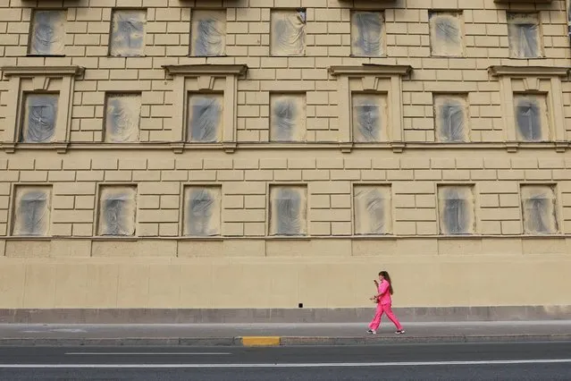 A woman wearing pink clothes walks past a painted facade in Saint Petersburg, Russia on August 27, 2023. (Photo by Anton Vaganov/Reuters)