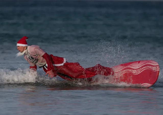 A surfer dressed as Santa falls off his surfboard as he braves the cold seas and near flat waves during the annual Surfing Santa as part of the Santa Run and Surf 2016 at Fistral Beach in Newquay on December 4, 2016 in Cornwall, England. (Photo by Matt Cardy/Getty Images)