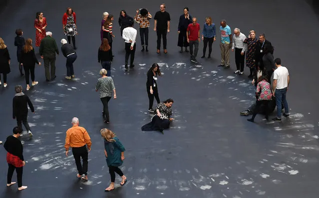 Cuban artist and activist Tania Bruguera (C) stands with volunteers on her installation during its unveiling in the Turbine Hall at Tate Modern in London, Britain, 01 October 2018. The art project created in response to the global migration crisis as part of the annual Hyundai Commission will be on show from 02 October 2018 to 24 February 2019. The installation “invites visitors to take part in symbolic actions by revealing a hidden image beneath a heat-sensitive floor”. (Photo by Andy Rain/EPA/EFE)