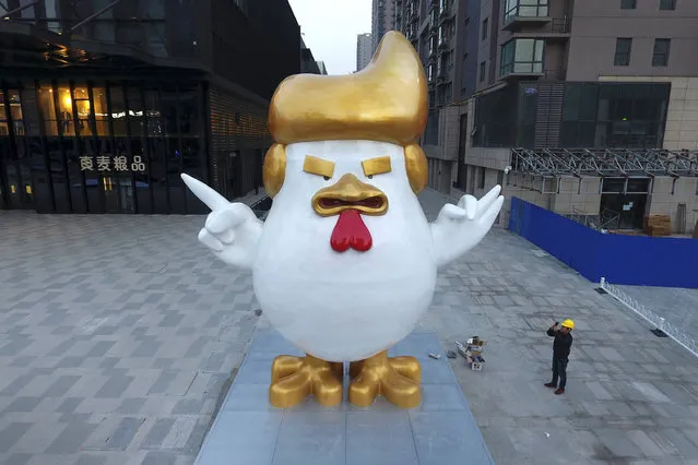 A worker takes a picture of a giant rooster sculpture resembling U.S. President-elect Donald Trump on display outside a shopping mall to celebrate the upcoming Chinese Year of the Rooster in Taiyuan in north China's Shanxi province, Thursday December 29, 2016. Trump has vowed to label China a currency manipulator on his first day in the White House. He says Beijing keeps its currency low to unfairly benefit its exporters. But he'll struggle to prove the case if it goes before the World Trade Organization: Economists say China isn't meddling in markets to push the yuan lower; it's doing the opposite, trying instead to keep it from falling faster. (Photo by Chinatopix via AP Photo)