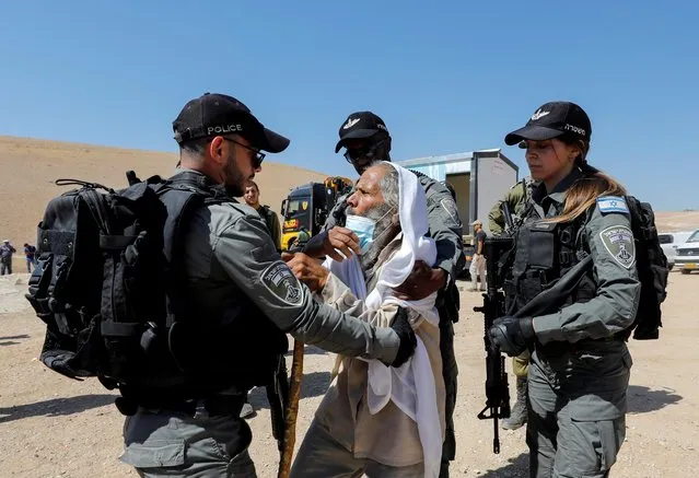 A Palestinian man scuffles with Israeli border police members as Israeli forces confiscate a healthcare clinic in Yatta, in the Israeli-occupied West Bank on July 12, 2021. (Photo by Mussa Qawasma/Reuters)