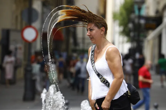 A woman cools off at a fountain in central Cordoba, southern Spain, 11 August 2021. Andalucia was put on orange alert for high temperatures, with a new heatwave forecast to reach temperatures of over 41 degrees Celsius in the region. (Photo by Salas/EPA/EFE)