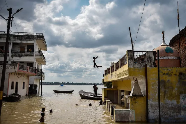 A child playfully jumps into the water accumulated at a flooded area next to a house after rising water levels in the rivers caused flooding at Jhusi area of Allahabad on August 6, 2021. (Photo by Sanjay Kanojia/AFP Photo)