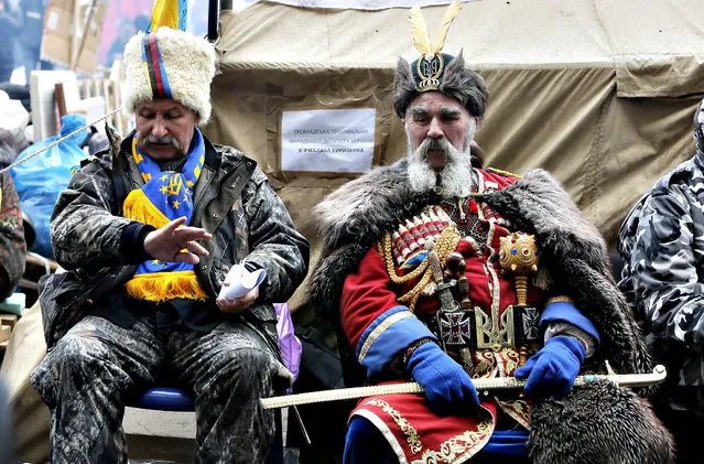 An Pro-European Union supporter dressed as Cossack has a rest at a tent camp in the city main street of Khreschatyk in Kiev Ukraine, Monday, December 16, 2013. Ukraine's opposition appears confident and shows no sign of relenting in its standoff with the government. The government has made some gestures toward the opposition, rejected some of its main demands and is opaque on another. (Photo by Efrem Lukatsky/AP Photo)