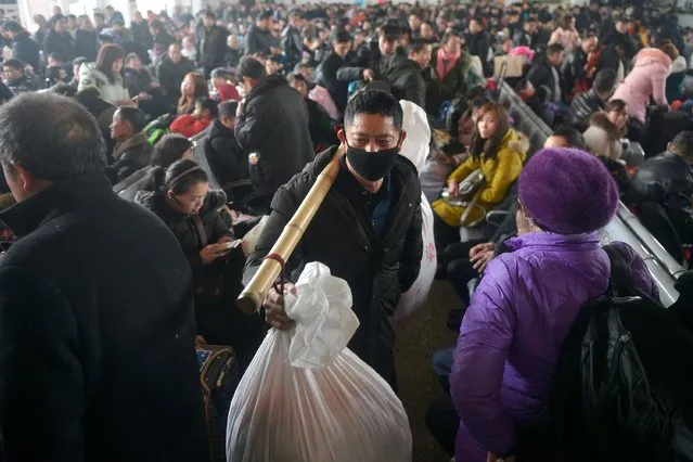 A man carries his belongings as he walks among passengers on the first day of the annual Spring Festival travel rush at a railway station in Jiaxing, Zhejiang province, January 21, 2019. (Photo by Reuters/China Stringer Network)