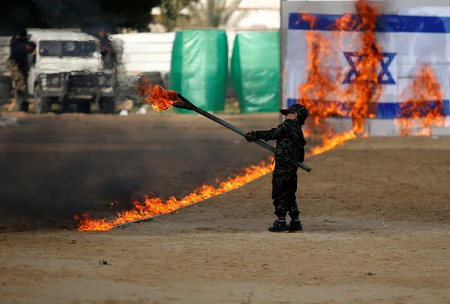 A Palestinian boy uses a torch to burn a mock Israeli army post as part of a drill during a graduation ceremony for members of Palestinian National Security Forces loyal to Hamas, in Gaza City January 22, 2017. (Photo by Suhaib Salem/Reuters)
