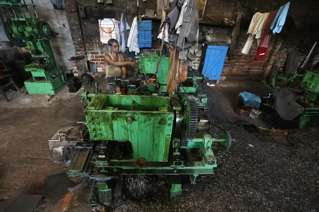 An employee operates a lathe machine as he makes spare parts of crops threshing machines inside a manufacturing unit in Kolkata, India, February 29, 2016. (Photo by Rupak De Chowdhuri/Reuters)