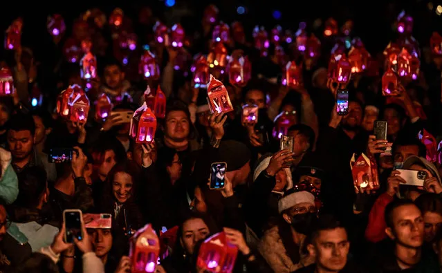 People hold candles on the Day of the Little Candles (Dia de las velitas), in Bogota on December 7, 2022. The Day of the Little Candles is a traditional Colombian celebration which commemorates the Immaculate Conception of the Virgin Mary and marks the beginning of the Christmas season. On this day, people light candles in their homes, on streets, and at cemeteries to decorate the graves of their loved ones. (Photo by Juan Barreto/AFP Photo)