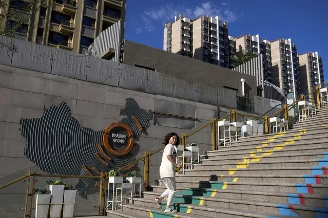 A woman looks back as she walks by a map showing Evergrande development projects with its apartment buildings seen behind, at an Evergrande city plaza in Beijing, Tuesday, September 21, 2021. Global investors are watching nervously as the Evergrande Group, one of China's biggest real estate developers, struggles to avoid defaulting on tens of billions of dollars of debt, fueling fears of possible wider shock waves for the Chinese financial system. (Photo by Andy Wong/AP Photo)