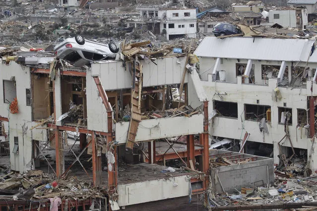 In this March 24, 2011 file photo, cars sit atop damaged buildings in Onagawa, Miyagi Prefecture, northeastern Japan after the March 11 earthquake and tsunami devastated the area. “My strongest memory was a scene I photographed in Onagawa: Cars on top of a three-story apartment building. It looked like their escape had been cut off and that they had been lifted up by the tsunami more than 20 meters (65 feet) above the ground. I was struck by the enormous power and ferociousness of nature. It looked like a scene from hell as I imagined that there were probably many dead bodies in the debris all around me”. – Koji Sasahara, AP photographer. (Photo by Koji Sasahara/AP Photo)