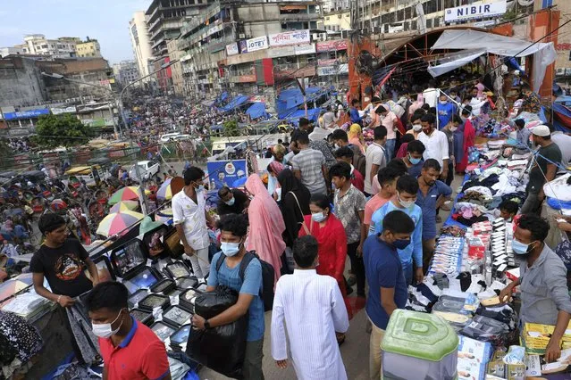 People shop at a market ahead of Eid-al Adha in Dhaka, Bangladesh, Friday, July 16, 2021. Millions of Bangladeshis are shopping and traveling during a controversial eight-day pause in the country’s strict coronavirus lockdown that the government is allowing for the Islamic festival Eid-al Adha. (Photo by Mahmud Hossain Opu/AP Photo)
