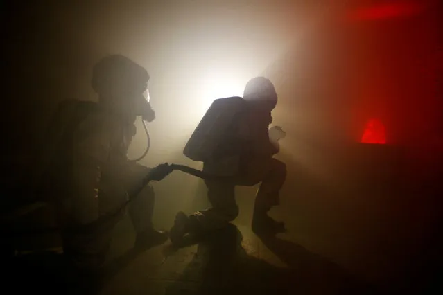 Students wears firefighting gears as they simulate a fire onboard a vessel at the French Navy school of Maistrance in Brest, Western France, February 2, 2017. (Photo by Charles Platiau/Reuters)