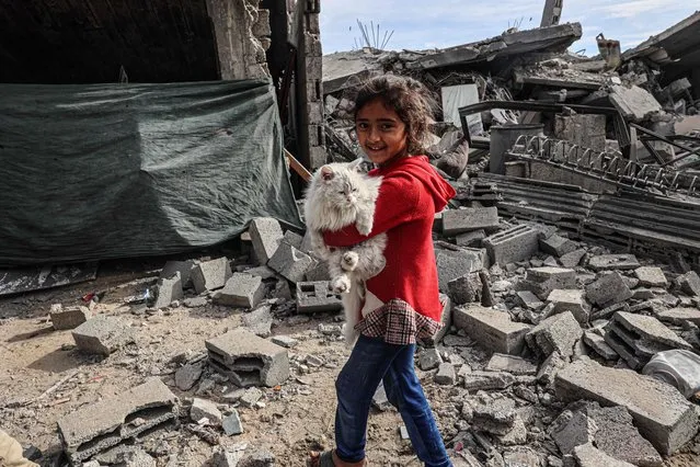 A Palestinian child carries a cat in the rubble of damaged buildings following Israeli bombardment in Rafah, on the southern Gaza Strip on February 12, 2024, amid ongoing battles between Israel and the militant roup Hamas. Israel announced on February 12 the rescue of two hostages in the southern Gaza city of Rafah, where the Hamas-run health ministry said “around 100” Palestinians including children were killed in heavy overnight air strikes. (Photo by Said Khatib/AFP Photo)