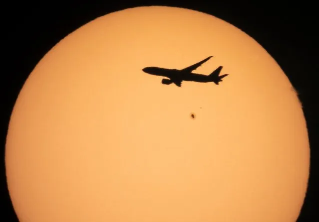 A cargo Boeing 777 of China Southern Airlines flying from Amsterdam to Shanghai is silhouetted against the Sun with a Sun spot, a result of solar activity, over the village of Podolye, 70 kilometeres (43 miles) east of St. Petersburg, Russia, Monday, October 11, 2021. (Photo by Dmitri Lovetsky/AP Photo)