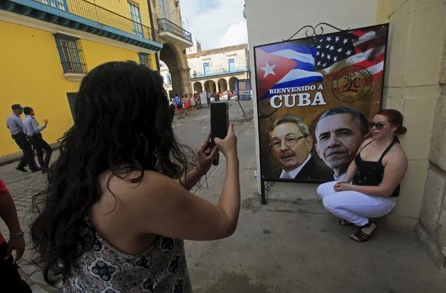 A visitor from California has her picture taken by a travel companian next to images of Cuba's President Raul Castro and U.S. President Barack Obama in Havana, Cuba March 19, 2016. The headline on the poster reads “Welcome to Cuba”. (Photo by Enrique De La Osa/Reuters)
