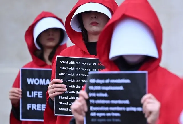 Protesters wearing “Handmaid's Tale” costumes, hold placards as they hold a silent march through central London on January 7, 2023, to raise awareness about the recent women-led uprising in Iran. (Photo by Justin Tallis/AFP Photo)