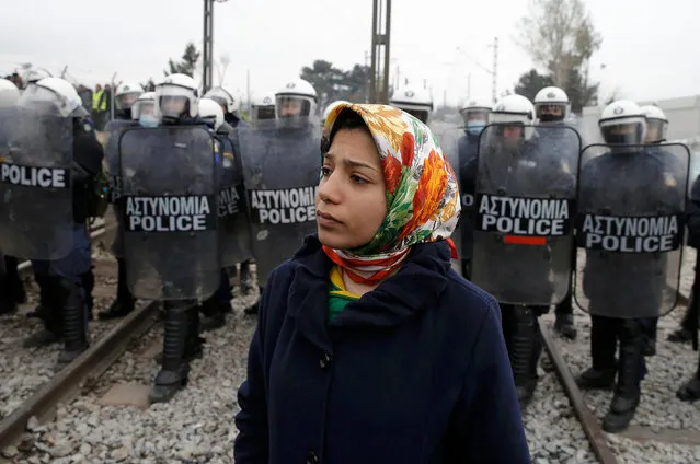 A migrant stands in front of Greek police during a protest at a makeshift camp near the village of Idomeni at the Greek-Macedonian border on March 27, 2016. (Photo by Marko Djurica/Reuters)