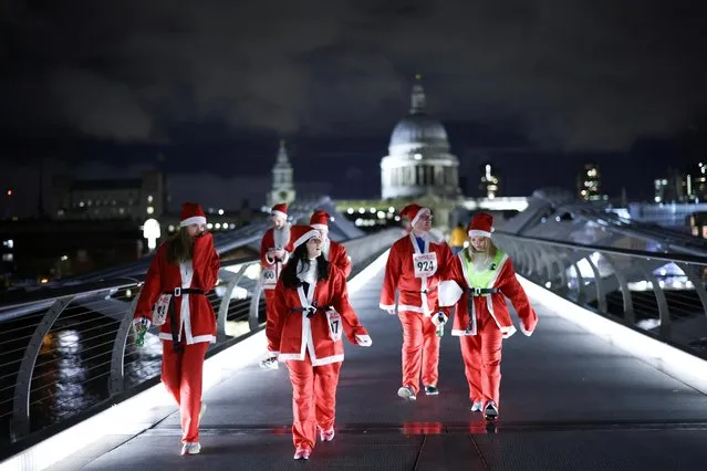 People dressed as Santa Claus walk over Millennium Bridge before taking part in a fun run on the South Bank in London, Britain, December 1, 2021. (Photo by Henry Nicholls/Reuters)