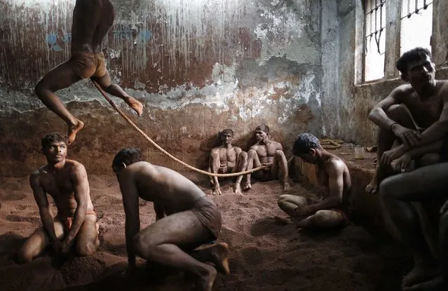 Wrestlers practise as others rest in the mud at a traditional Indian wrestling centre called Akhaara in Mumbai March 4, 2014. Kushti (mud wrestling) is a traditional sport in India but more and more young athletes are now training to wrestle on mats instead of mud to gain access to top international competitions like the Olympic Games or the Commonwealth Games. (Photo by Danish Siddiqui/Reuters)