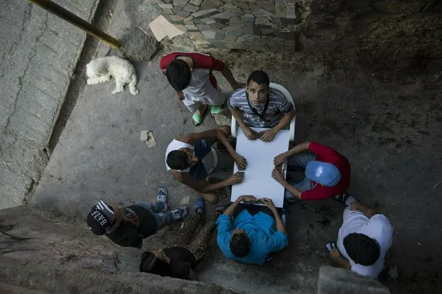 Men play dominoes in the Petare shanty town, in Caracas, Venezuela, Friday, May 3, 2019. (Photo by Rodrigo Abd/AP Photo)
