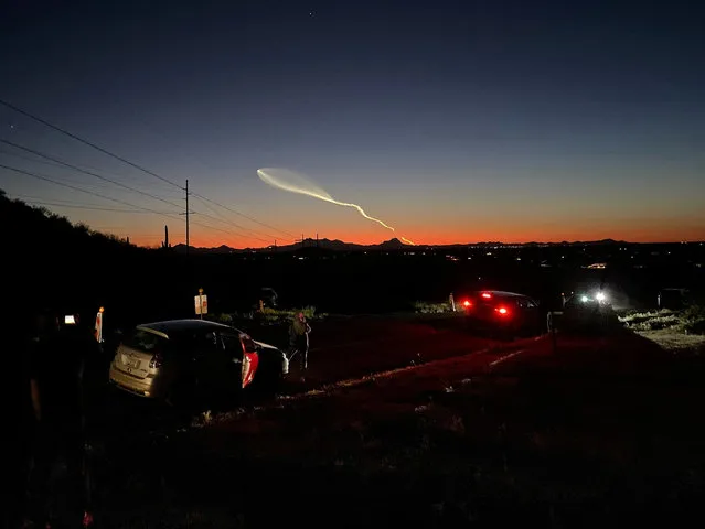 People watch as a SpaceX Falcon 9 rocket carrying 21 Starlink satellites passes after its launch from Vandenberg Space Force Base in neighboring California, on a hill in Marana, Arizona on April 6, 2024. (Photo by Nancy Lapid/Reuters)