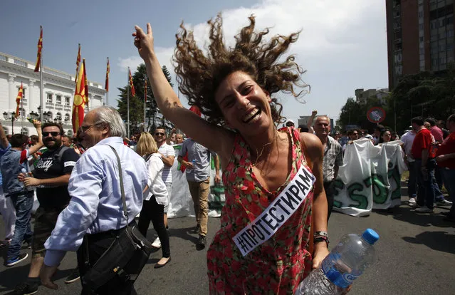 A woman dances while protesting in front of the Government building in Skopje, Macedonia, on Sunday, May 17, 2015. Macedonian opposition started massive demonstrations Sunday in Skopje protesting against the conservative government of the Prime Minister Nikola Gruevski, demanding its resignation. The banner strip reads “I Ptotest”. (Photo by Boris Grdanoski/AP Photo)