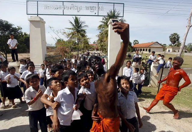 Villagers with painted faces, take selfies with students as they march along a street during the annual “Lok Ta Pring Ka-Ek” religious ceremony, on the outskirts of Phnom Penh May 22, 2015. (Photo by Samrang Pring/Reuters)