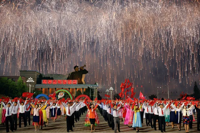 Fireworks explode over participants in a mass dance in the capital's main ceremonial square, a day after the ruling Workers' Party of Korea party wrapped up its first congress in 36 years, in Pyongyang, North Korea, May 10, 2016. (Photo by Damir Sagolj/Reuters)