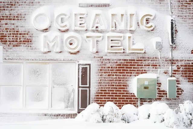 Signage outside of a motel is covered in snow, Saturday, January 29, 2022, in Ocean City, Md. A powerful nor'easter swept up the East Coast on Saturday, threatening to bury parts of 10 states under deep, furiously falling snow accompanied by coastal flooding and high winds that could cut power and leave people shivering in the cold weather expected to follow. (Photo by Julio Cortez/AP Photo)