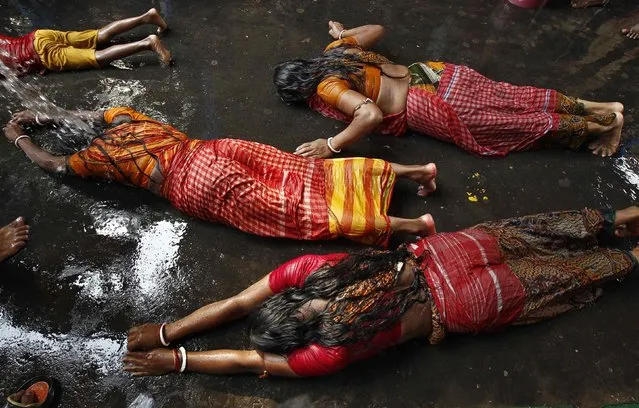 Women lie on a road during a ritual as they worship Sheetala Mata, the Hindu goddess of smallpox, during the Sheetala Puja in Kolkata April 19, 2014. During the Puja, women fast for the whole day to pray for the betterment of their family and society. (Photo by Rupak De Chowdhuri/Reuters)