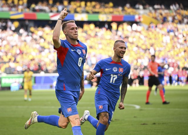 Slovakia's Ondrej Duda, left, celebrates scoring the opening goal against Romania during a Group E match at the Euro 2024 soccer tournament in Frankfurt, Germany, Wednesday, June 26, 2024. (Photo by Arne Dedert/dpa via AP Photo)