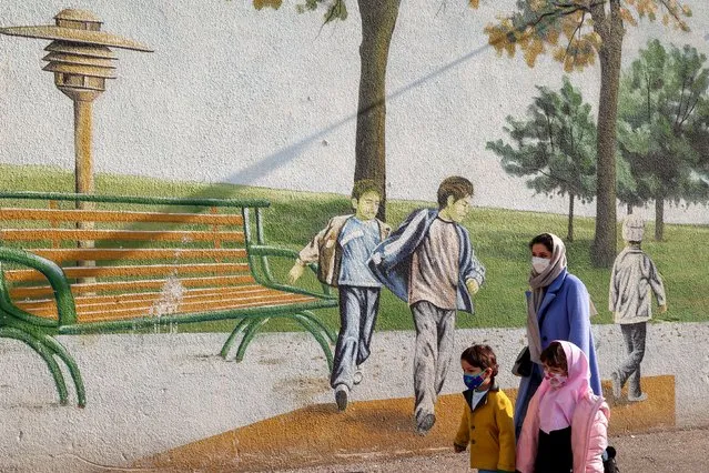 A woman and children walk past a mural at a park in the Iranian capital Tehran on December 29, 2021. Iran said earlier this week that nuclear talks in Vienna should focus on lifting sanctions on the Islamic republic and “guarantee” the US will return to the fold. Negotiations to salvage the 2015 Iran nuclear deal resumed in late November, after a five-month hiatus following the election of ultraconservative Iran President Ebrahim Raisi. (Photo by Atta Kenare/AFP Photo)