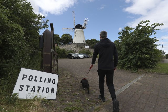 A man and his dog walk towards Falwell windmill and mill which is a temporary polling station in Sunderland, England, Thursday, July 4, 2024.Britain goes to the polls Thursday after Prime Minister Rishi Sunak called a general election. (Photo by Scott Heppell/AP Photo)