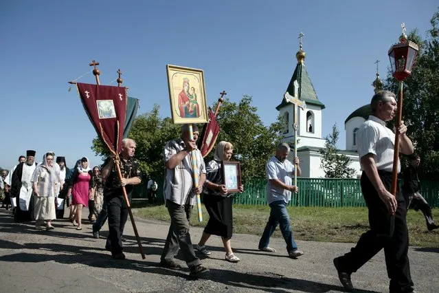 People take part in a procession to attend a commemoration ceremony near the site of the Malaysia Airlines flight MH17 plane crash in the village of Hrabove in Donetsk region, Ukraine, July 17, 2015. (Photo by Kazbek Basaev/Reuters)