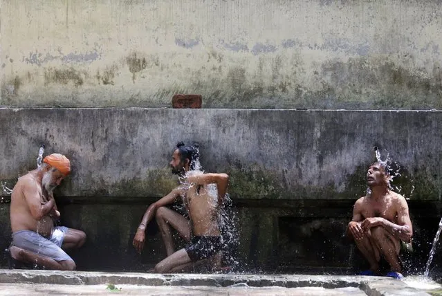 Indian men take bath at a common bathing place on a hot and sunny day in Amritsar, India, 17 May 2016. According to weather reports, Amritsar is expriencing severe heat wave with temperatures hovering around 42 degrees Celsius mark. (Photo by Raminder Pal Singh/EPA)