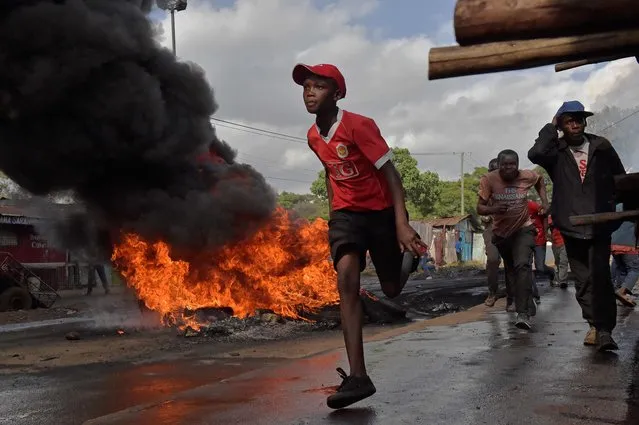 A boy runs past a burning barricade in Kibera slum during a demonstration of opposition supporters protesting for a change of leadership ahead of a vote due next years on May 23, 2016 in Nairobi. (Photo by Carl De Souza/AFP Photo)