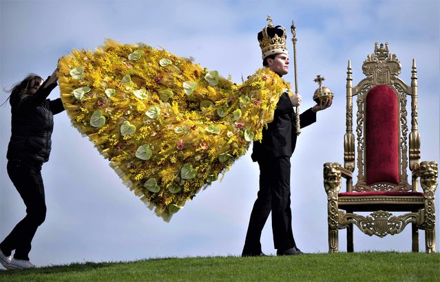 Model Rupert North (R) has his attire adjusted as he wears a floral Coronation cloak, designed by florist Helen James, along with replicas of the St Edward's Crown, Sovereign's Sceptre with Cross and Sovereign's Orb during a photocall for a Coronation-themed floral display, on the eve of the Harrogate Spring Flower Show, at The Great Yorkshire Showground in Harrogate, northern England, on April 19, 2023. (Photo by Oli Scarff/AFP Photo)