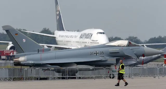 A technician walks past a German Air Force Eurofighter combat aircraft and Ed Force One, the plane of British heavy metal band Iron Maiden at the ILA Berlin Air Show in Schoenefeld, south of Berlin, Germany, May 31, 2016. (Photo by Fabrizio Bensch/Reuters)