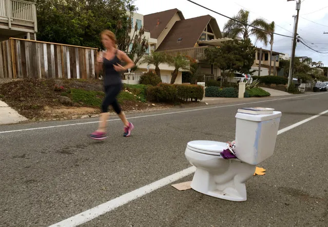 An early morning runner jogs past a toilet placed on the side of the road for free pick-up to any passerby in Leucadia, California, United States May 24, 2016. (Photo by Mike Blake/Reuters)